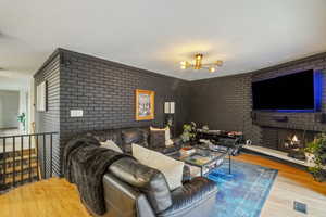 Living room featuring brick wall, light hardwood / wood-style floors, and a brick fireplace