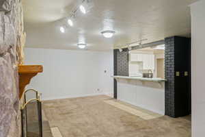 Kitchen featuring a breakfast bar area, light colored carpet, kitchen peninsula, and white cabinets