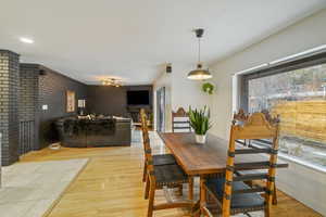 Dining area with brick wall and light wood-type flooring