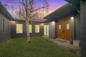 Exterior entry at dusk with a lawn