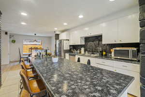 Kitchen with sink, a kitchen island, pendant lighting, stainless steel appliances, and white cabinets