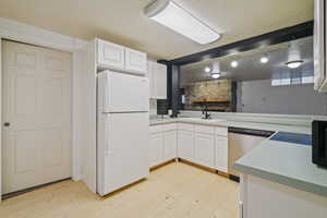 Kitchen with white refrigerator, dishwasher, sink, and white cabinetry