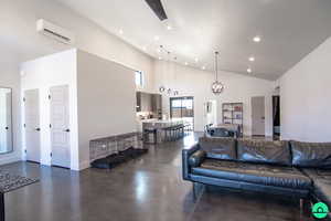 Living room with an inviting chandelier, high vaulted ceiling, and a wall unit AC