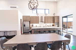 Dining space featuring concrete flooring, sink, a wall mounted AC, a notable chandelier, and a high ceiling