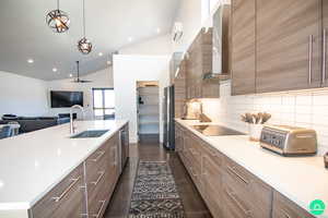 Kitchen featuring appliances with stainless steel finishes, sink, backsplash, hanging light fixtures, and wall chimney range hood