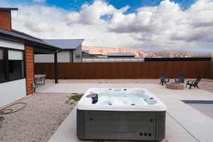 View of patio with a hot tub, a mountain view, and a fire pit