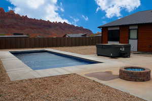 View of pool featuring a hot tub, a mountain view, a fire pit, and a patio