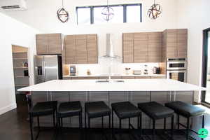 Kitchen with pendant lighting, a wall mounted AC, a kitchen bar, stainless steel appliances, and wall chimney exhaust hood