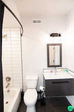 Full bathroom with vanity, tiled shower / bath combo, and toilet