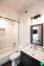 Full bathroom featuring vanity, tiled shower / bath combo, and toilet