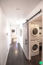 Laundry room featuring stacked washer and clothes dryer and a barn door