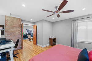 Bedroom featuring a barn door, hardwood / wood-style floors, and ceiling fan