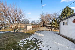 Yard layered in snow with a shed