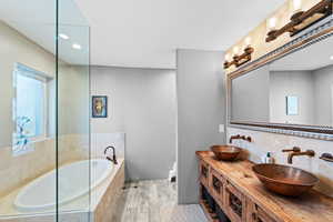 Bathroom with tasteful backsplash, tiled tub, vanity, and hardwood / wood-style flooring