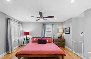 Bedroom with ceiling fan, multiple windows, and light wood-type flooring