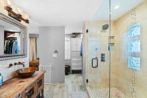 Bathroom with walk in shower, wood-type flooring, radiator heating unit, vanity, and backsplash