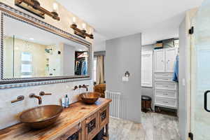 Bathroom featuring radiator, a shower with shower door, decorative backsplash, hardwood / wood-style flooring, and vanity