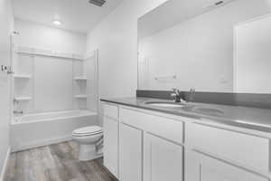 Full bathroom with hardwood / wood-style flooring, shower / bathtub combination, vanity, and toilet