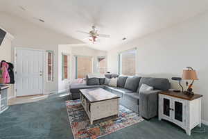 Carpeted living room with lofted ceiling and ceiling fan