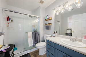 Bathroom featuring an enclosed shower, vanity, tile patterned flooring, and toilet