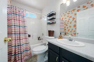 Full bathroom with shower / bath combination with curtain, vanity, and toilet