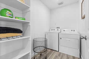 Washroom with light hardwood / wood-style flooring and washing machine and dryer