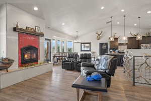 Living room featuring light hardwood / wood-style flooring, a chandelier, and vaulted ceiling