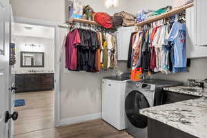 Laundry area with cabinets, sink, washing machine and clothes dryer, and light hardwood / wood-style flooring