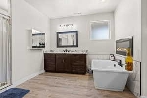 Bathroom featuring hardwood / wood-style flooring, vanity, shower with separate bathtub, and a textured ceiling