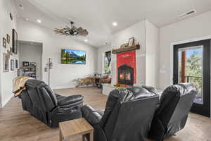 Living room with vaulted ceiling, ceiling fan, and light wood-type flooring