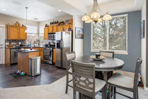 Kitchen with appliances with stainless steel finishes, decorative light fixtures, sink, decorative backsplash, and a center island