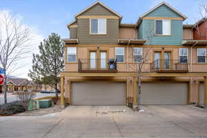 View of property with french doors, a balcony, and a garage