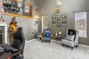 Office with a high ceiling, a tile fireplace, and light colored carpet