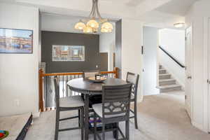 Carpeted dining space with an inviting chandelier