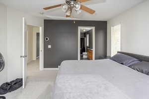 Carpeted bedroom with ceiling fan and ensuite bathroom