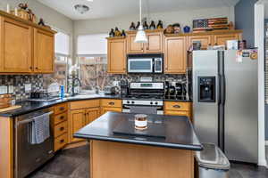 Kitchen featuring appliances with stainless steel finishes, a center island, sink, and backsplash