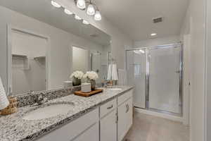 Bathroom featuring tile patterned flooring, vanity, and a shower with shower door