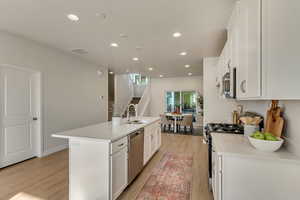 Kitchen with white cabinetry, sink, an island with sink, and appliances with stainless steel finishes