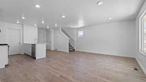 Unfurnished living room with sink, a textured ceiling, and light wood-type flooring