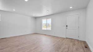 Empty room with a textured ceiling and light wood-type flooring