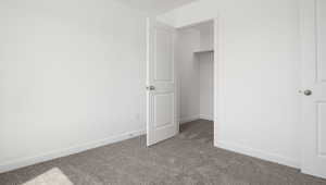 Unfurnished bedroom with a spacious closet, carpet floors, and a closet