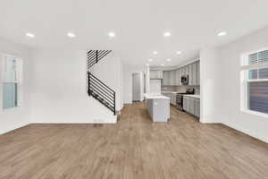 Kitchen featuring a kitchen bar, gray cabinetry, a center island, appliances with stainless steel finishes, and light hardwood / wood-style floors