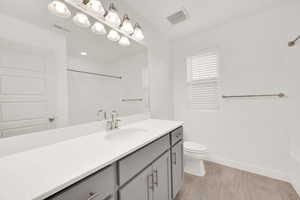 Bathroom with walk in shower, vanity, toilet, and wood-type flooring