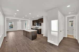 Kitchen featuring sink, dark hardwood / wood-style flooring, dark brown cabinetry, stainless steel appliances, and a center island with sink