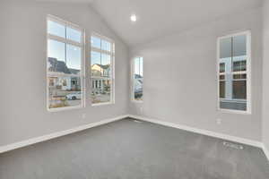 Empty room featuring vaulted ceiling and carpet flooring