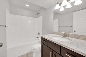 Full bathroom featuring bathing tub / shower combination, hardwood / wood-style floors, vanity, a textured ceiling, and toilet