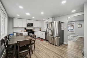 Kitchen featuring white cabinetry, sink, stainless steel appliances, and light wood-type flooring