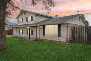 Back house at dusk featuring a yard