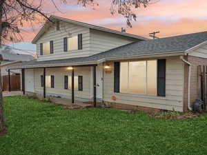 Back house at dusk featuring a yard