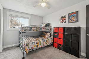 Carpeted bedroom featuring ceiling fan and a textured ceiling